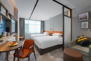 ein Hotelzimmer mit 2 Betten und einem Tisch in der Unterkunft Home2 Suites By Hilton Wuhan Hankou Railway Station in Wuhan
