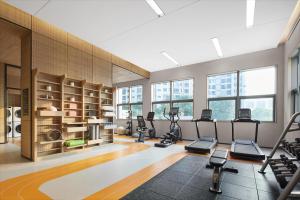 a gym with treadmills and ellipticals in a room with windows at Home2 Suites By Hilton Wuhan Hankou Railway Station in Wuhan