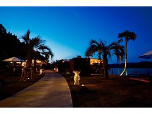 een stoep met palmbomen, een gebouw en een straat bij Glamping village Seagrand in Matsuura