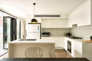 una cucina bianca con armadi bianchi e lavandino di Retreat on Darling - Harbour Views 3 Bed a Sydney