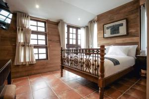 a bedroom with a bed with wooden walls and windows at Gavill15 Classic Boutique House in Chiang Mai