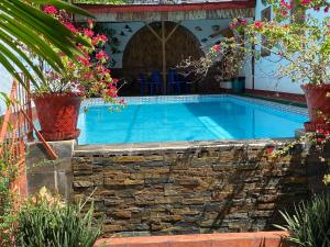 a swimming pool with a stone wall and flowers at Villa del Mar in Mactan