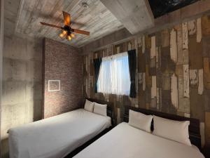 2 łóżka w pokoju z wentylatorem sufitowym w obiekcie Wolf Pack Apartment 1001 w Osace