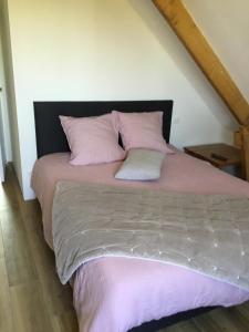 a bedroom with a bed with pink sheets and pillows at La Malvrais in Janzé