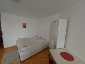 a small white bedroom with a bed and a cabinet at Studios & Apartments Perla in Sunny Beach