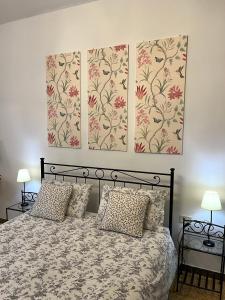 フィレンツェにあるLa Corte Apartmentのベッドルーム1室(壁に2枚の写真が飾られたベッド1台付)