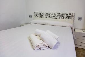 a white bed with two towels on it at Apartment Triana in Seville