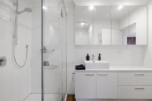 a white bathroom with a shower and a sink at A Stylish and Unique Retreat at Surf Beach in Surf Beach