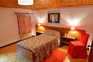 1 dormitorio con 1 cama y 1 silla roja en B&B Casa di Campagna, en Miane