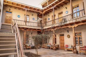 um edifício com varandas e mesas e cadeiras de madeira em Salom Inn em Bukhara