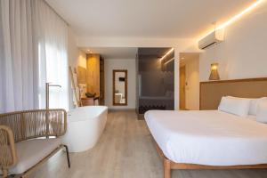 ein Schlafzimmer mit einem großen Bett und einer Badewanne in der Unterkunft Play Hotel Ibiza - Adults Only in Ibiza-Stadt