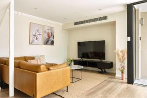 a living room with a couch and a tv at Retreat on Darling - Harbour Views 3 Bed in Sydney