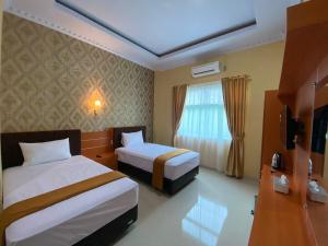 a hotel room with two beds and a window at Wisma Jannatun Naim Lampung in Lampung +6 photos