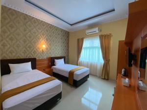 a hotel room with two beds and a window at Wisma Jannatun Naim Lampung in Lampung