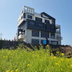 a building on top of a hill with a field of flowers at Eutteum-won Pension in Jeju