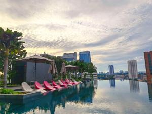 a row of chairs and umbrellas next to a body of water at Opus Residences Kuala Lumpur by Luna in Kuala Lumpur