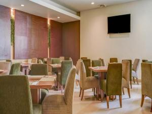 a dining room with tables and chairs and a flat screen tv at Grand Cikarang Hotel in Tegalgede