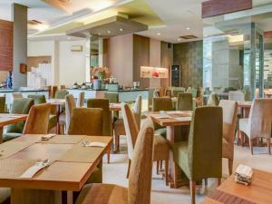 a dining room with wooden tables and chairs at Grand Cikarang Hotel in Tegalgede