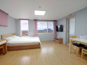 a bedroom with a bed and a desk and a television at Eutteum-won Pension in Jeju