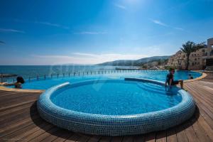 un niño parado junto a una piscina al lado del océano en Marina Balchik apartment, en Balchik