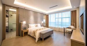 a bedroom with a bed and a desk and a window at Qingyuan Argyle Hotel in Qingyuan