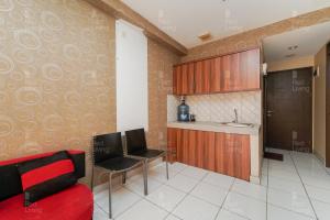 uma sala de estar com um sofá vermelho e uma cozinha em RedLiving Apartemen Mekarwangi Square - Agus 3 Tower A em Bandung