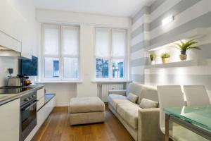 sala de estar con sofá y algunas ventanas en Easylife - San Babila - Elegante e rifinito bilocale nel cuore della città, en Milán