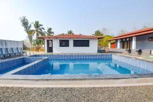 a swimming pool in front of a house at FabEscape Kautilyaa Resort With Swimming Pool 