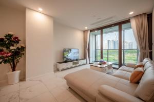 sala de estar con sofá blanco y TV en The Metropoles - Sy's Home, en Ho Chi Minh