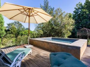 um pátio com um guarda-sol e uma piscina em Devon Castle Forest Lodge em Stellenbosch