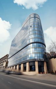 a tall glass building with a road in front of it at Royal Tulip Hotel & Casino, Tbilisi in Tbilisi City