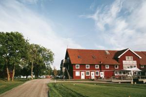 a large red barn with a red roof on a dirt road at Strand Golf in Harad