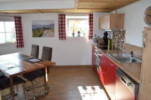 a kitchen with red cabinets and a wooden table at Ferienwohnung Bergkristall in Oberstdorf