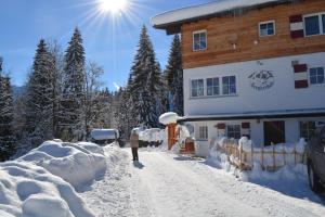 uma pessoa de pé na neve em frente a um edifício em Ferienwohnung Bergkristall em Oberstdorf