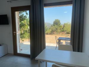 Zimmer mit einem Tisch und einer Glastür mit Aussicht in der Unterkunft Casa Vacanze Alba in Loceri