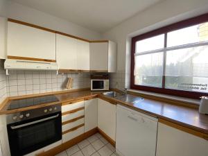 a kitchen with white cabinets and a sink and a window at Ferienwohnung-Peter-Pan-mit-Sonnenterrasse-Garten-zwischen-Strand-Wald-Wiese-auf-Ruegen in Gustow
