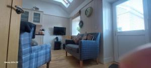 a living room with two chairs and a clock on the wall at Fairdene Cottage in Ballater