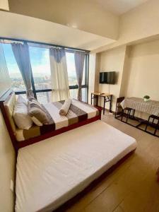 a large bed in a room with a large window at AFFORDABLE StayCation EASTWOOD CITY in Manila