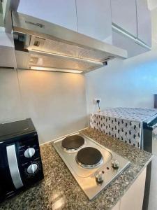 a kitchen with a stove top with a microwave at AFFORDABLE StayCation EASTWOOD CITY in Manila