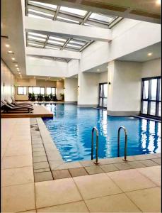 a large swimming pool with blue water in a building at AFFORDABLE StayCation EASTWOOD CITY in Manila