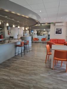 un vestíbulo con mesas y sillas naranjas y una cafetería en ACE Hôtel Travel Fabrègues - A9 Montpellier Sud, en Fabrègues