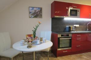 eine Küche mit roten Schränken und einem kleinen weißen Tisch in der Unterkunft Apartmán U Josefa in Sušice