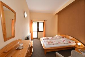 1 dormitorio con cama, mesa y espejo en Penzión Lesnica, en Spišské Tomášovce