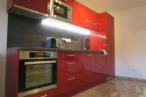 eine Küche mit roten Schränken und einer Mikrowelle in der Unterkunft Apartmán U Josefa in Sušice