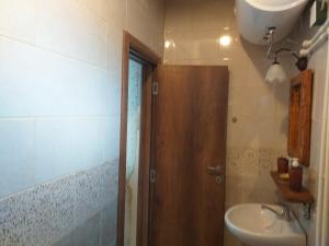 a bathroom with a sink and a wooden door at Restuarant-Apartments T'ga za jug Lazaropole in Lazaropole
