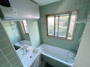 een groene betegelde badkamer met een bad en een wastafel bij Entiry apartment, Private rooms in Paris in Parijs