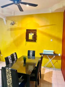 comedor con mesa y pared amarilla en Idaman Sinar Homestay en Nibung Tebal