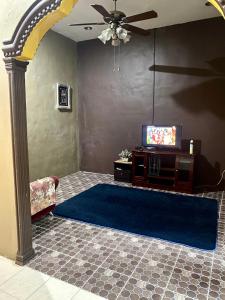 a living room with a blue rug and a tv at Idaman Sinar Homestay in Nibung Tebal