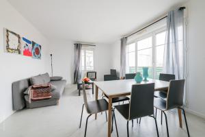 ein weißes Wohnzimmer mit einem Tisch und Stühlen in der Unterkunft Les 2 Lys in Brétigny-sur-Orge