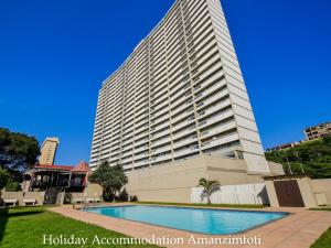 a large building with a swimming pool in front of it at Holiday Accommodation Amanzimtoti in Amanzimtoti